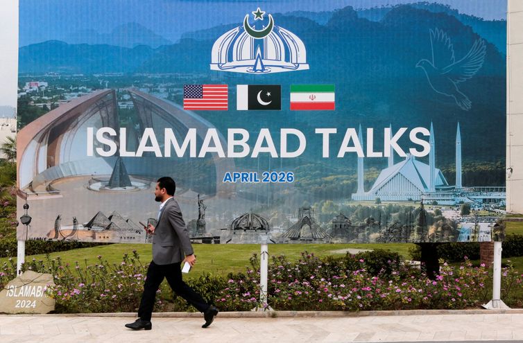 Reuters/Asim Hafeez/Proibida reprodução A man walks past a billboard near the media centre as delegations from the United States and Iran are expected to hold peace talks in Islamabad, Pakistan, April 11, 2026. REUTERS/Asim Hafeez TPX IMAGES OF THE DAY REFILE - CHANGING FROM